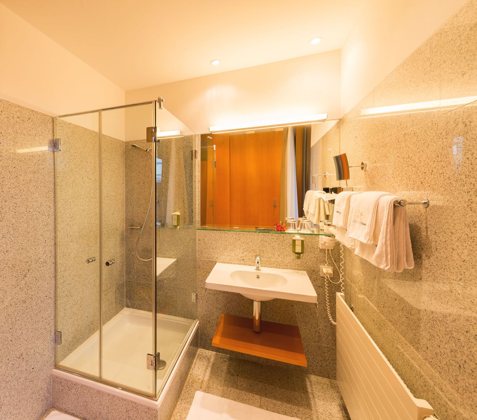 Badezimmer eines Standard Einzelzimmer mit Dusche, Waschbecken, Spiegel, aufgehängten Handtüchern
