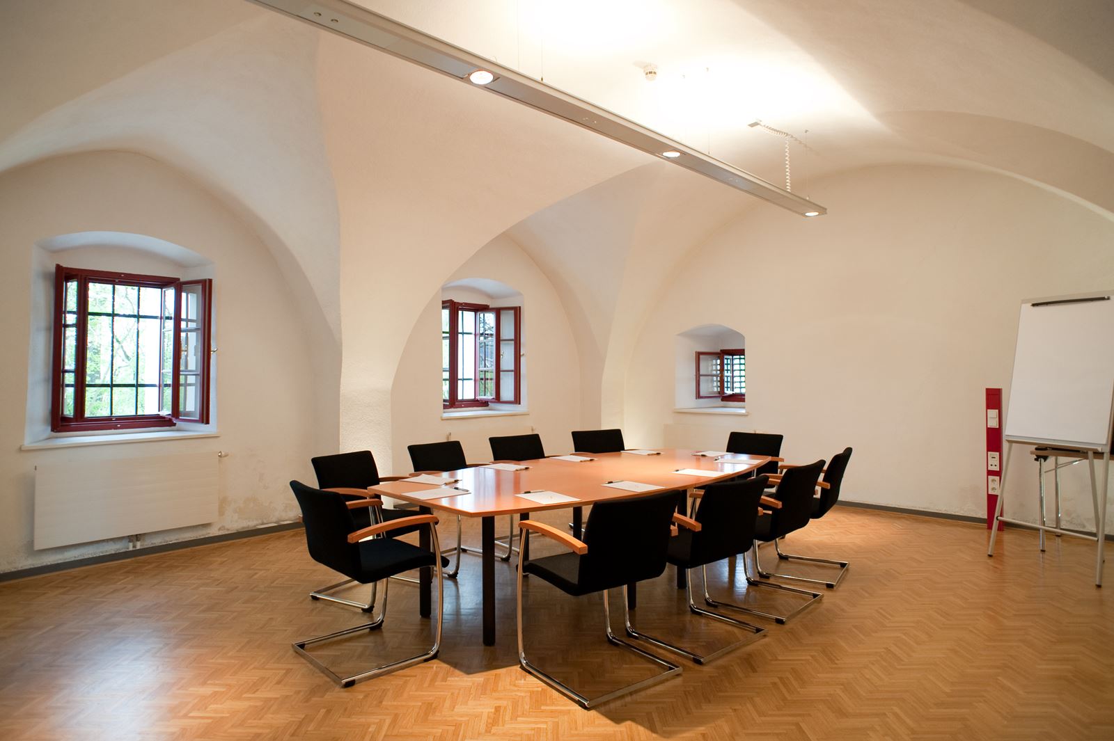 Brennersaal2 mit rundem Tisch und Sesseln und Flip Chart