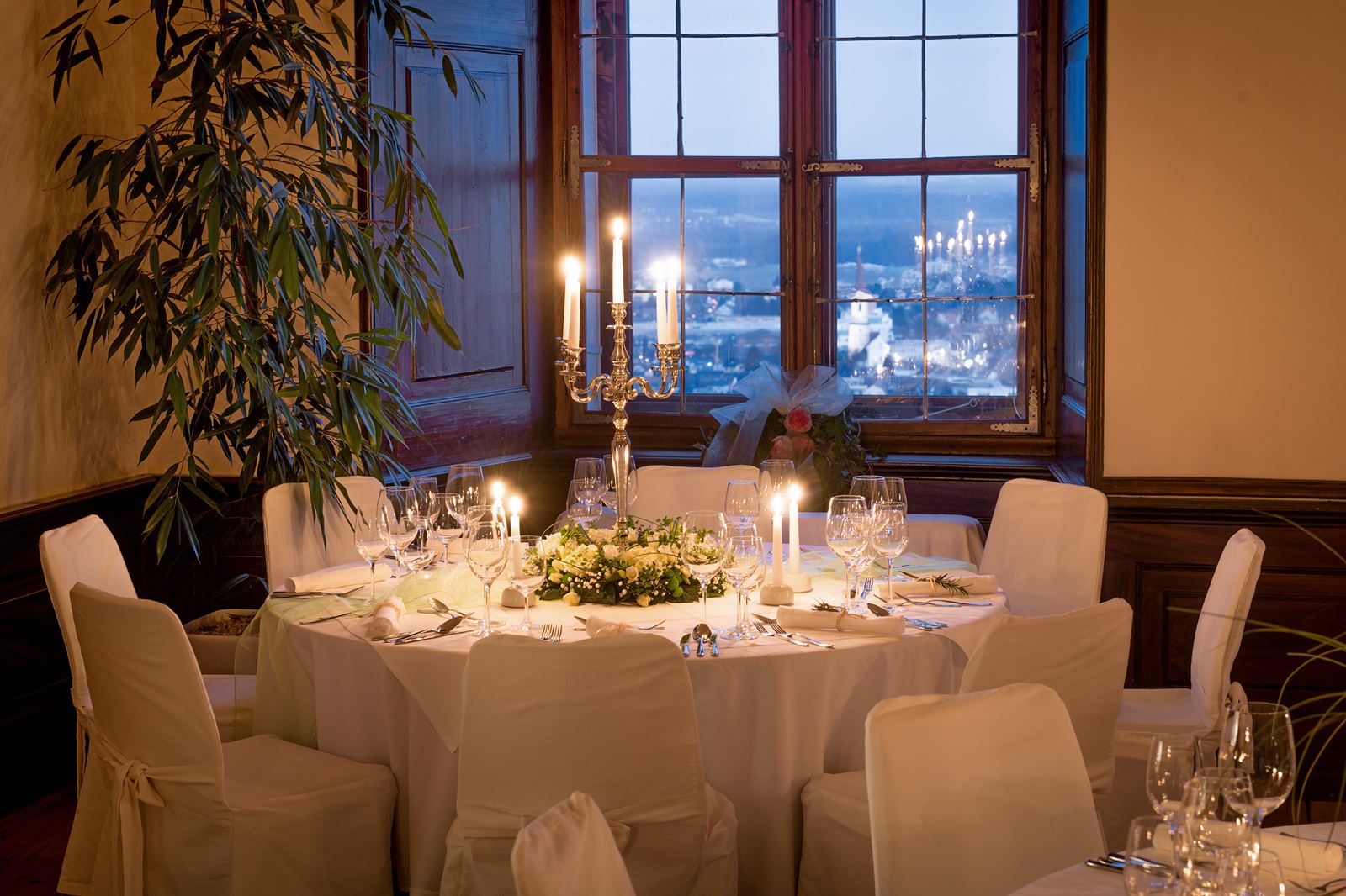Festlich gedeckter runder Tisch im Oberschloss. Der Blick führt über die beleuchtete Stadt Leibnitz