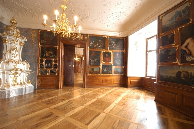 The prince´s room with old paintings on the walls, an old baroque tiled stove and an old chandelier